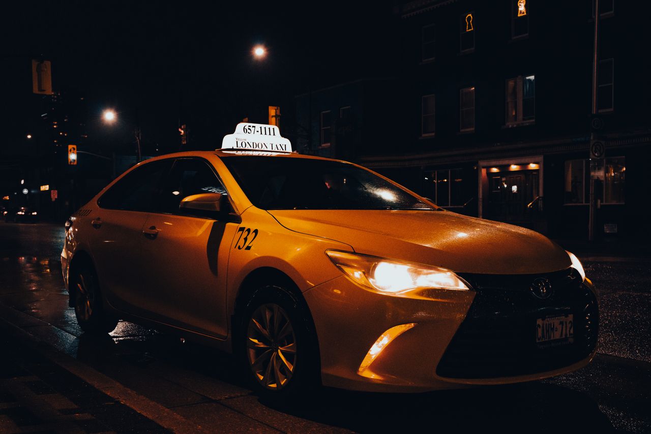 Home A yellow taxi waiting at night in London, Ontario, Canada. Urban transportation captured with street lights.