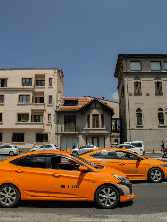 About Street view of yellow taxis in front of historic buildings under clear blue sky.