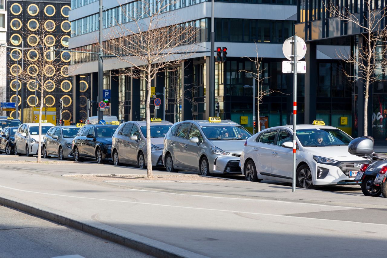 Home A lineup of taxis on an urban street with modern buildings in the background.