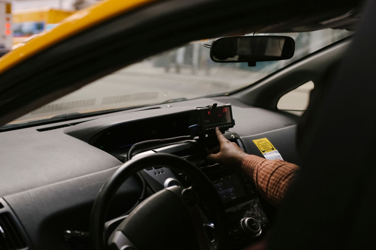 Anonymous ethnic male driver with steering wheel using GPS navigator to search direction for drive on street in city during work